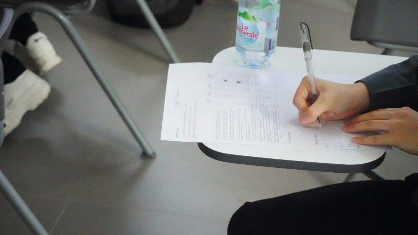 Candidate handwriting an IELTS essay under timed exam conditions on paper