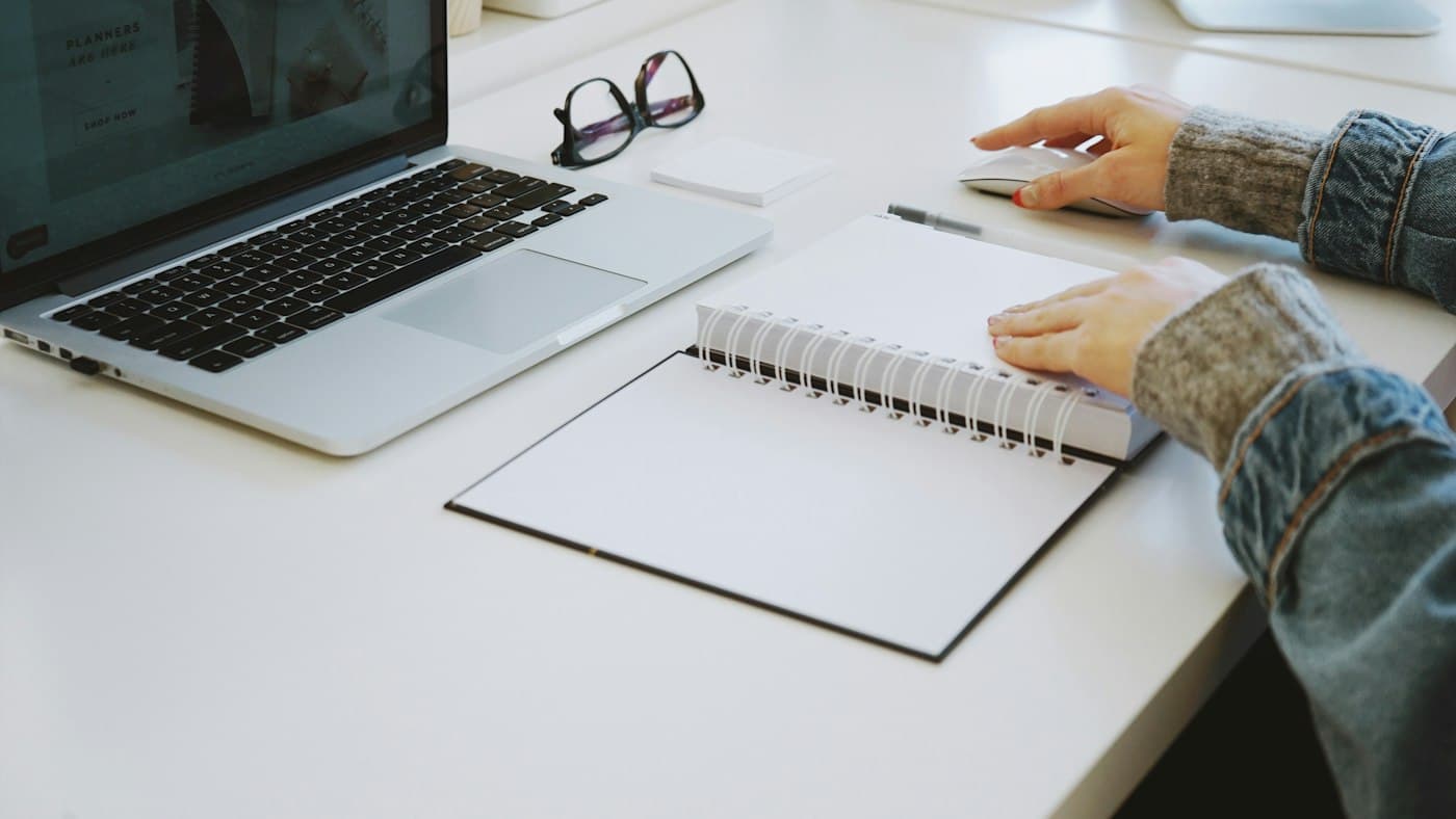 Teacher pausing over a blank notebook while planning a lesson with AI help
