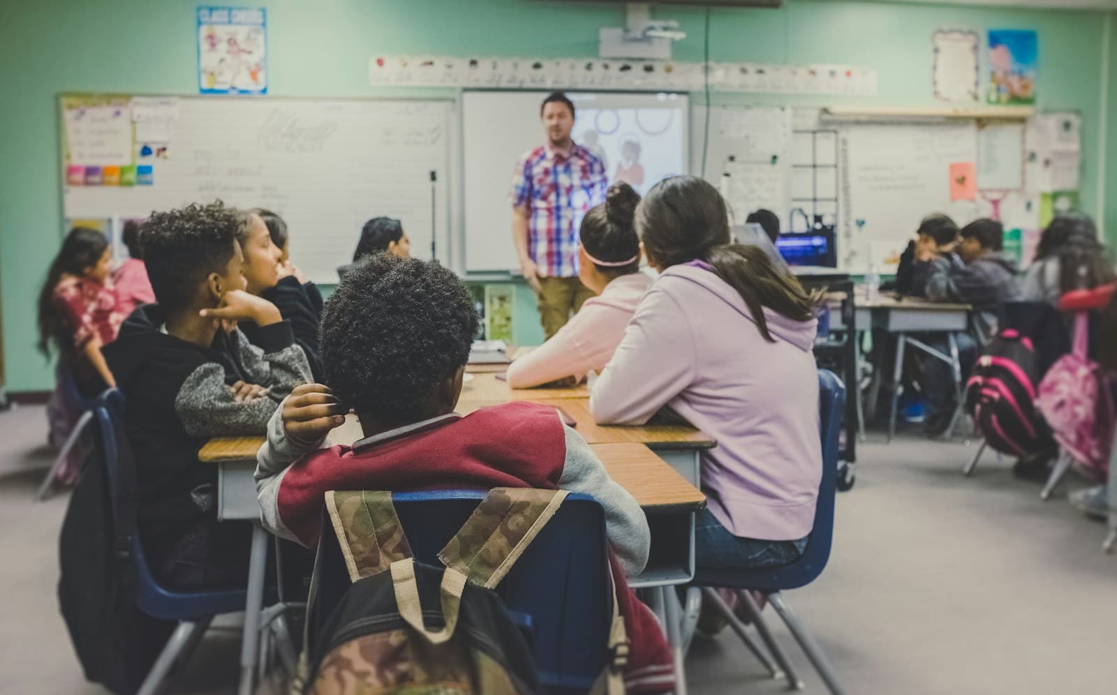 English teacher presenting present perfect tense grammar to adult learners in a classroom